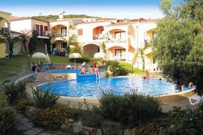 A pool area with multiple pools, lounge chairs, and umbrellas. - Apartment with pool in the Residence Badus (Badesi)