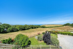 A rural landscape with rolling hills, a clear sky, and a fenced area with greenery. - Beach Life, Cabin Vibes, Ocean Views nr Bude (Bude)