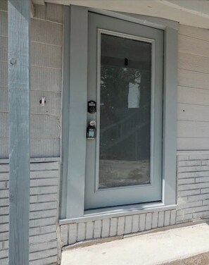 A gray-framed door with a glass panel, a keypad lock, and a small window above the door. - AAV Home Unit#B New!!1BR Near Fort Sam/Pearl/DT (San Antonio)