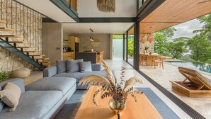 Una sala moderna con sofá, mesa de centro y vistas a una piscina.