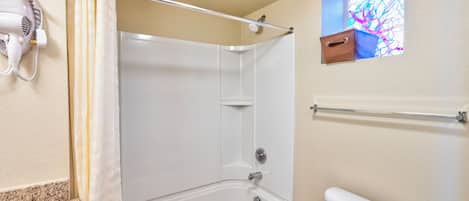 Un baño con ducha, inodoro y ventana con vista a un diseño de vitral.