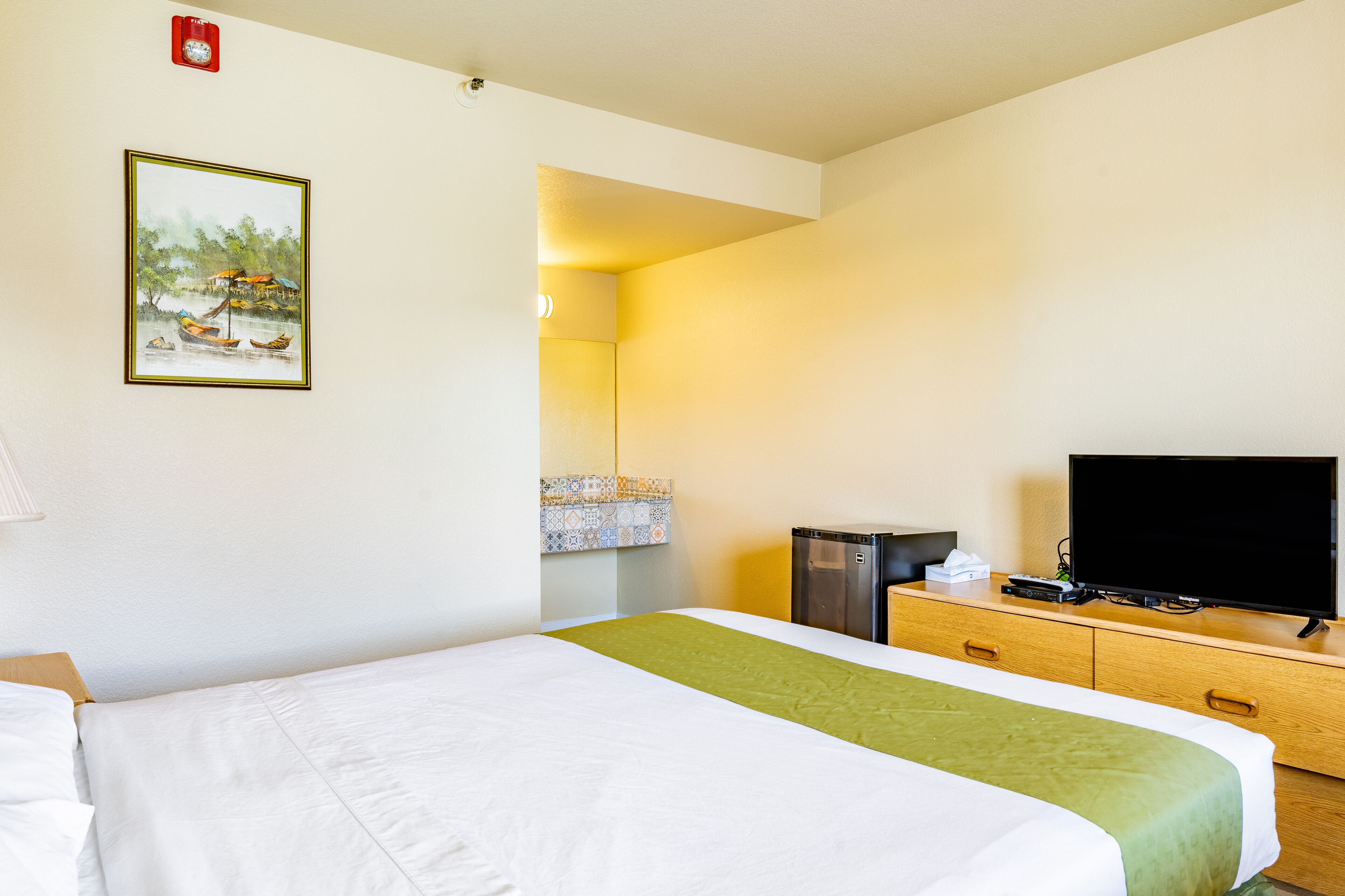 Een hotelkamer met een bed, een televisie, een dressoir en een schilderij aan de muur.