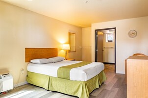 Habitación de hotel con cama, lámpara de noche, cabecero de madera y escritorio.