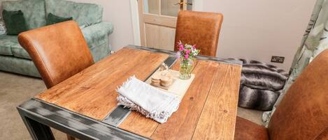 A dining area with a wooden table, four brown leather chairs, a green sofa, and a door with a glass panel.
