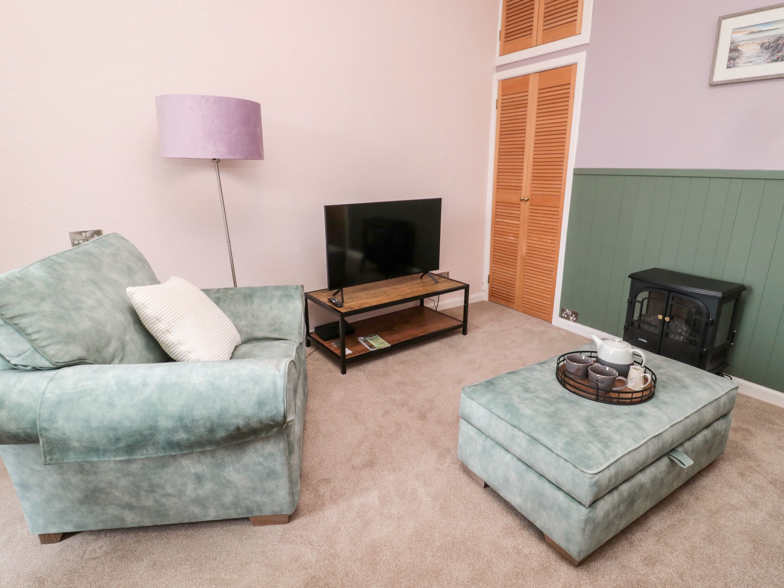 A living room with a sofa, a coffee table, a television, a lamp, and a fireplace.