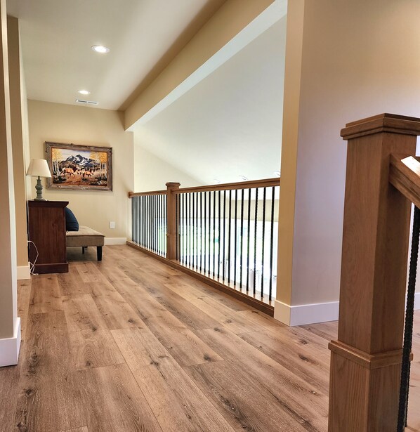 A wooden-floored hallway with a wooden railing, a bench, and a painting on the wall. - New home in the heart of Alpine! (Alpine)