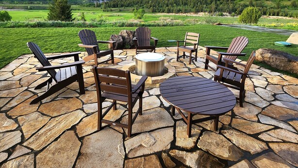 A stone patio with Adirondack chairs and a fire pit, overlooking a mountainous landscape. - New home in the heart of Alpine! (Alpine)