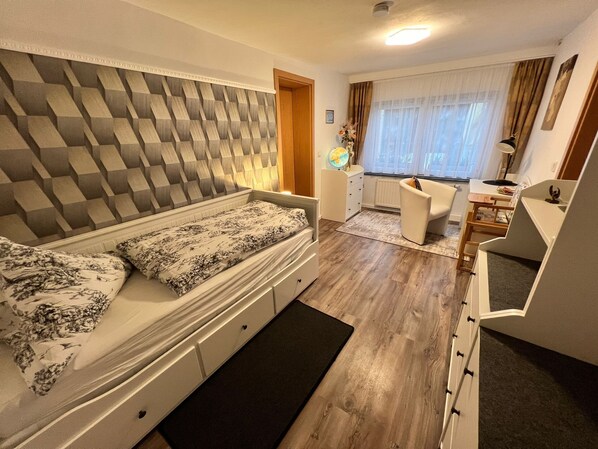 A compact bedroom with a bed, a small desk, and a chair. - Modern 4-star apartment - stylish comfort, relaxation for people and dogs! (Weißenfels)