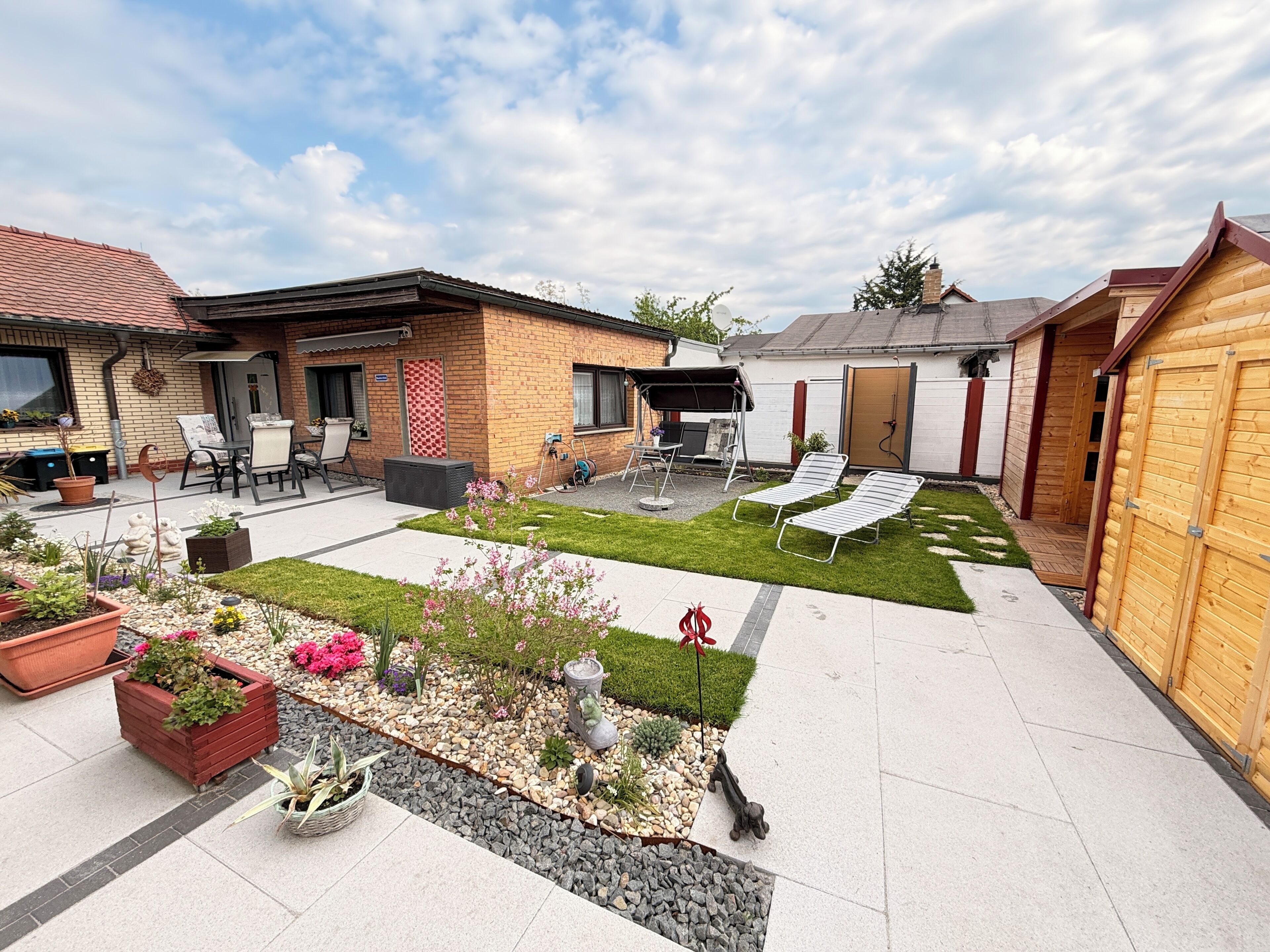A backyard with a patio, seating area, and a small garden.