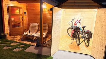 A wooden cabin with a covered patio area, a bicycle, and outdoor seating.