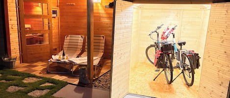 Una cabaña de madera con un porche cubierto, una bicicleta y mobiliario para exteriores.