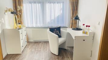A modern, well-lit room with a white desk, a comfortable chair, and a radiator.