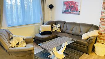 A living room with a brown sofa, a brown armchair, and a coffee table with a geometric patterned rug.