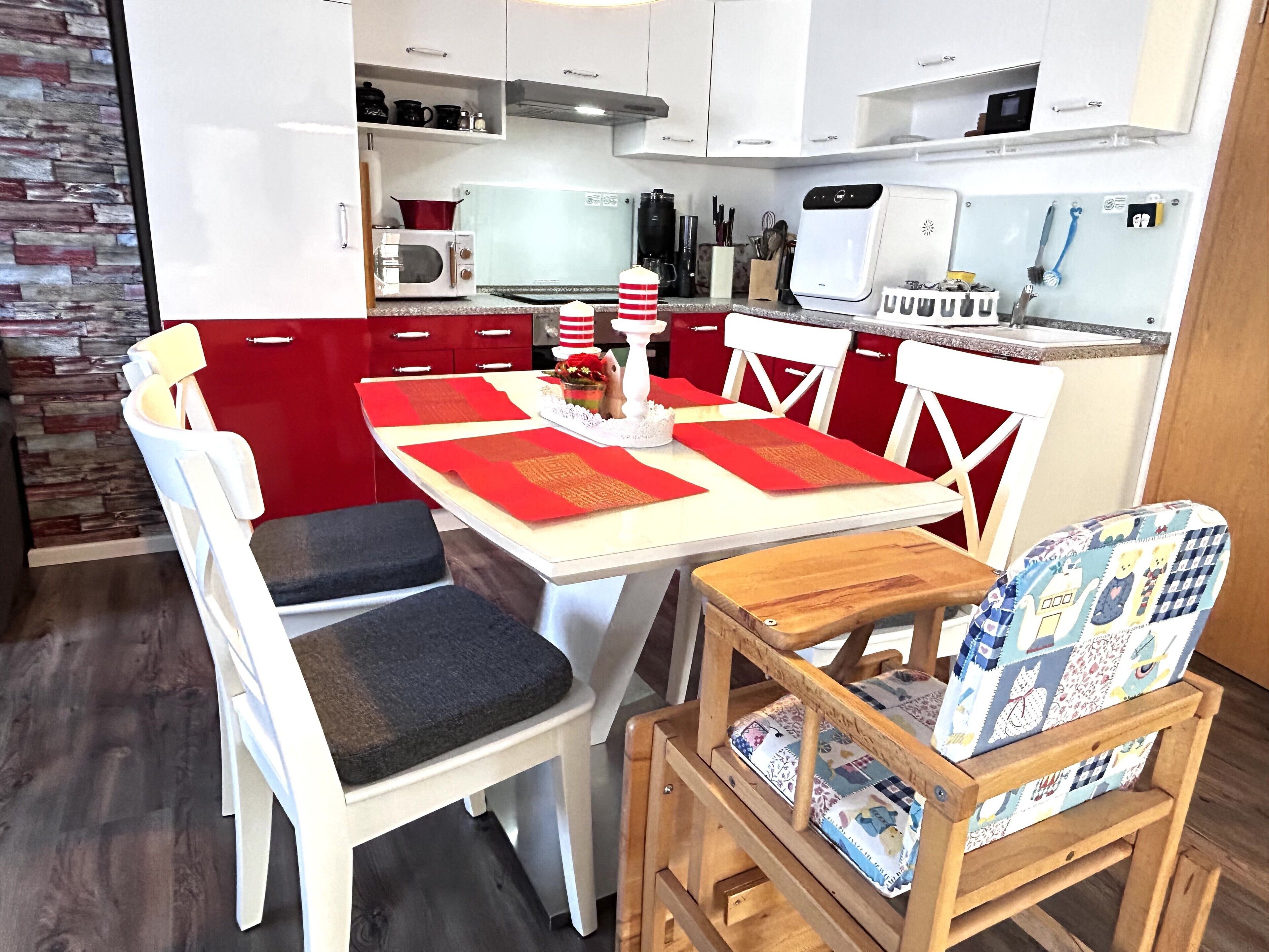 A compact kitchen with white cabinets, a microwave, a coffee maker, and a small dining area with a table and chairs.
