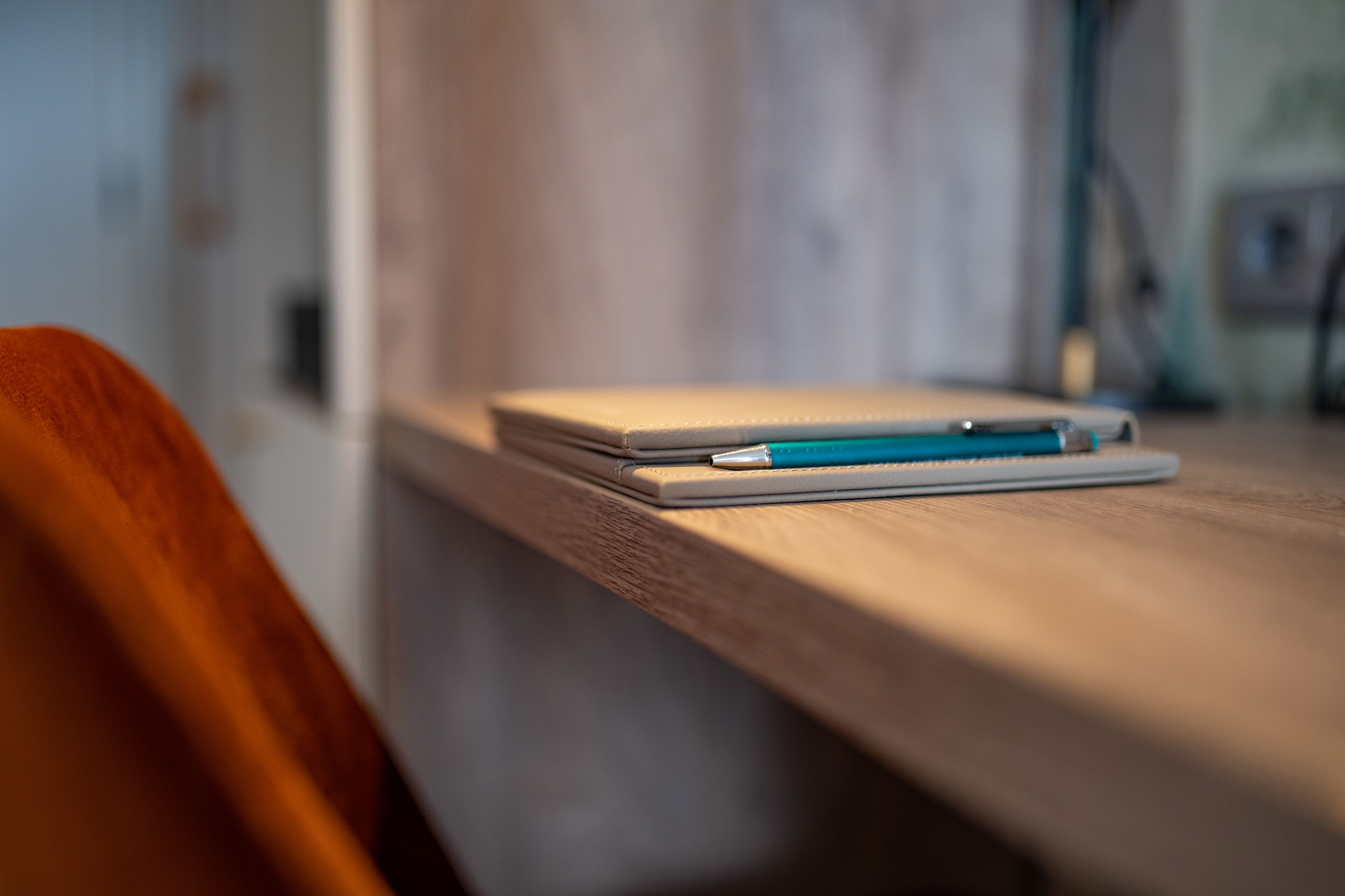 A wooden table with a notebook and pen.