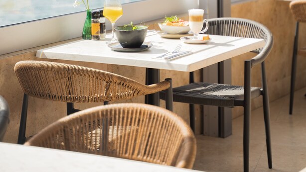 Un comedor con una mesa dispuesta para dos, con vista a un cuerpo de agua.