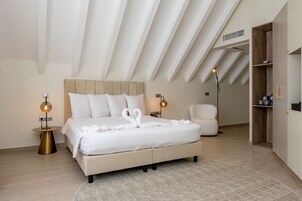 A modern bedroom with a large bed, two bedside tables, a chair, and a built-in wardrobe.