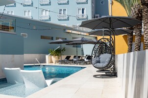 Una piscina al aire libre, sombrillas, sillones reclinables de piscina