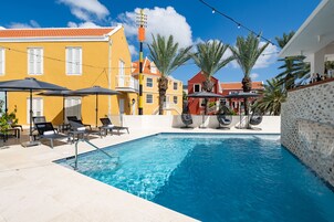 Una piscina al aire libre, sombrillas, sillones reclinables de piscina
