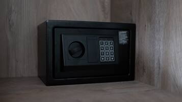 A black safe with a keypad and a keyhole, placed on a wooden shelf.