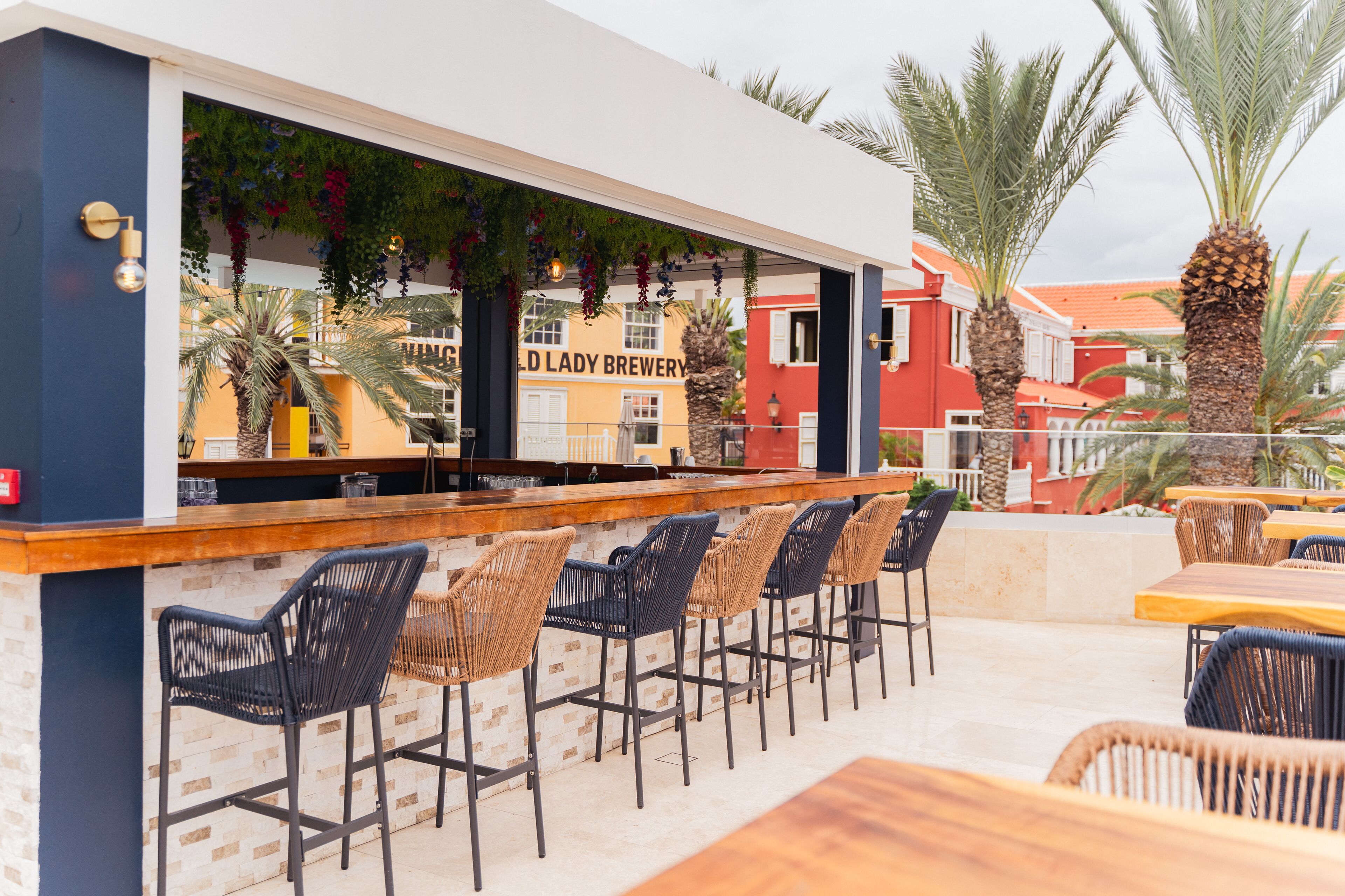 Un área de bar al aire libre con sillas de mimbre y una barra que muestra el letrero "OLD LADY BREWERY".
