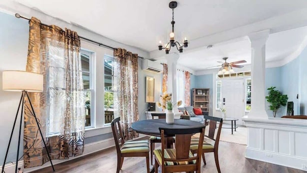 A dining area with a round table, chairs, a chandelier, and curtains. - Cozy Springfield Abode - AC, Wifi, WD (Jacksonville)