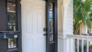 A black door with a white number '2' sign, a white door, and a white railing with a plant. - Cozy Springfield Abode - AC, Wifi, WD (Jacksonville)