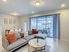 Relax in this stylish living room with a comfortable sofa, coffee table, and sliding glass door leading to an outdoor dining area.