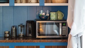 A kitchen counter with a microwave, a coffee maker, and a bowl of flowers. - Selkies Cave (Union)