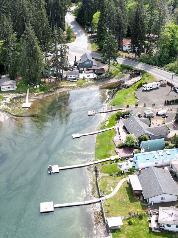 An aerial view of a lakeside community with houses, a dock, and a road curving through the area. - Selkies Cave (Union)