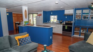 A modern kitchen with blue walls, wooden cabinets, and a central island. - Selkies Cave (Union)