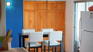 A kitchen with wooden cabinets, a dining table with two chairs, and a refrigerator. - Selkies Cave (Union)