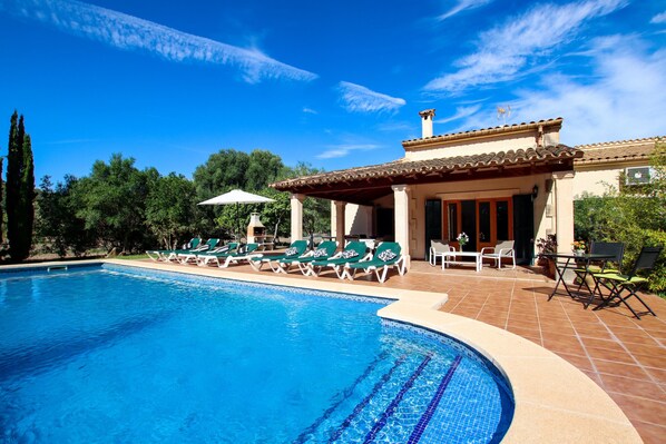 Ein Pool mit Liegestühlen und einer überdachten Terrasse.
