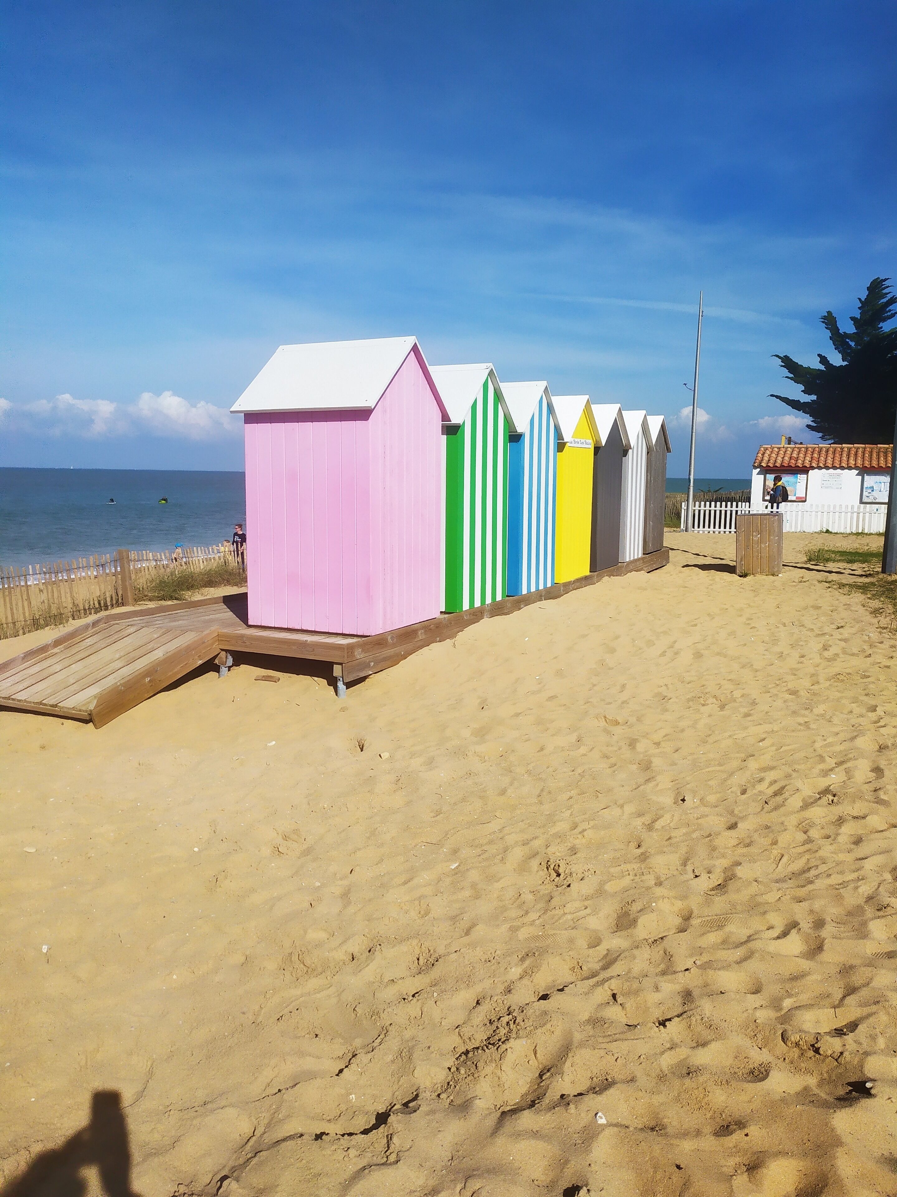Une rangée de cabanes de plage colorées, avec une terrasse en bois devant.