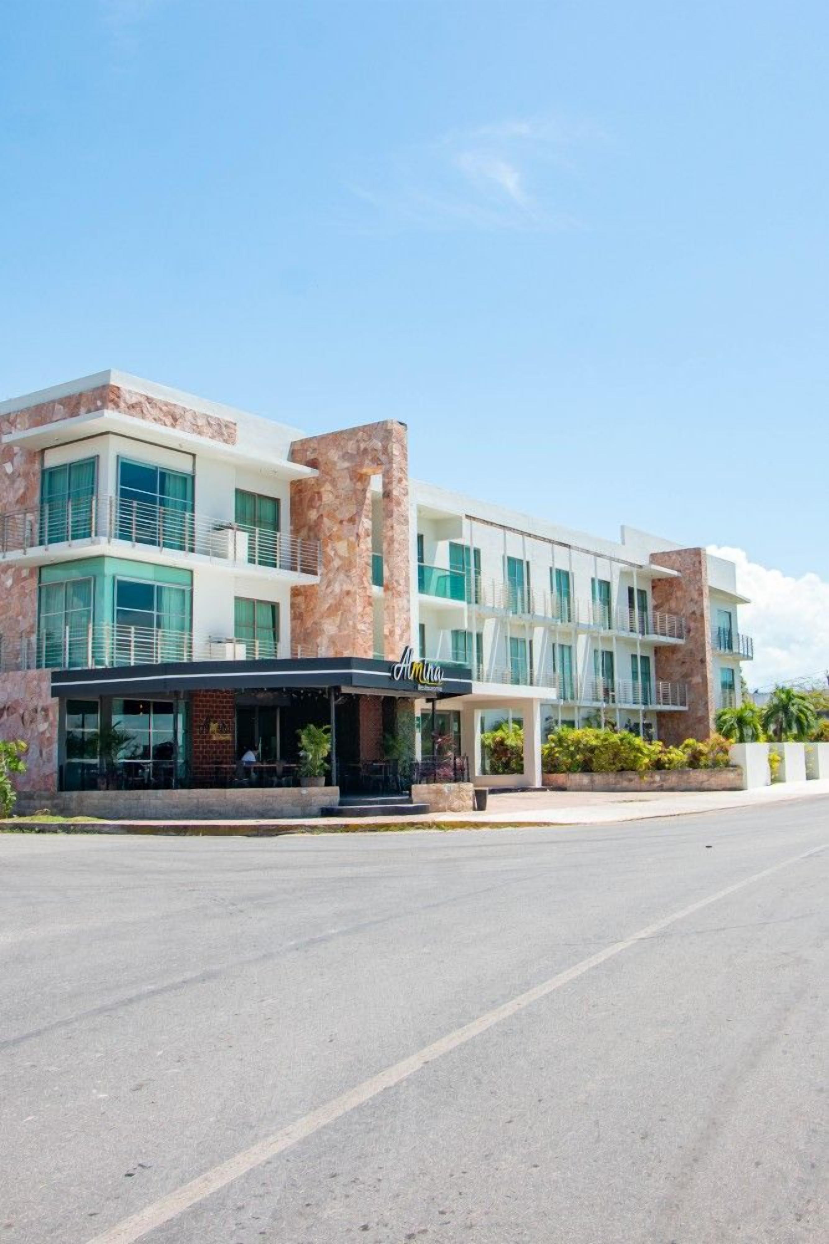 A modern hotel with a two-story structure, a covered outdoor seating area, and a clear sky.