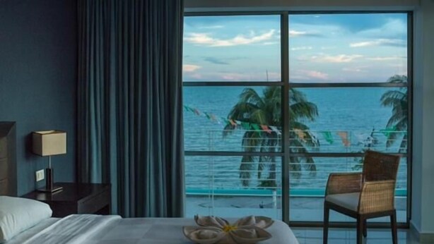 A hotel room with a large window overlooking a pool and the sea. - Hotel Noor (Chetumal)