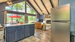 A modern kitchen with a large island, dark cabinetry, and a stainless steel refrigerator. - Pet-Friendly Stanwood Sanctuary w/ Fire Pit! (Stanwood)