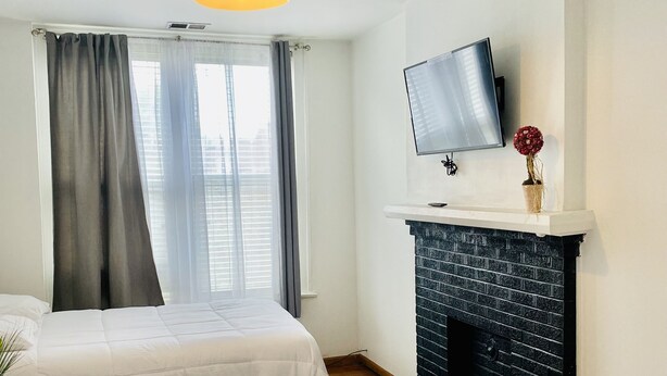 A hotel room with two beds, a flat-screen TV mounted above a fireplace, and a window with curtains.