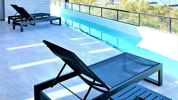 An outdoor terrace with a pool, lounge chairs, and a view of the city. - Stylish apartment by river with pool & grill (Olivos)