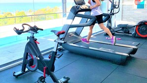 A gym with a treadmill, stationary bike, and elliptical machine. - Stylish apartment by river with pool & grill (Olivos)