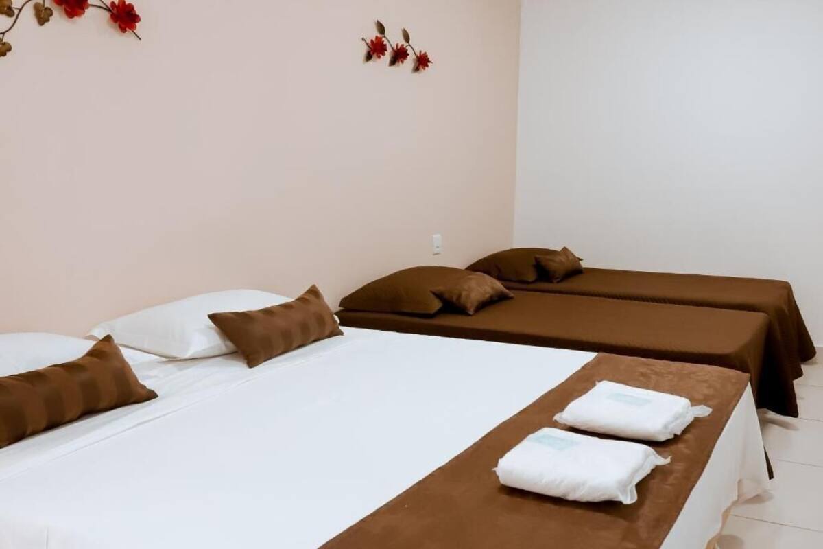 Hotellihuone, jossa on kaksi sänkyä, ruskeat vuodevaatteet, valkoiset tyynyt ja ruskea pääty.