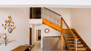 A modern interior with a wooden staircase, a dining area with a bench, and a wall-mounted clock. - Pousada Shalom Capitólio (Capitólio)