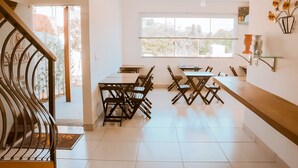 A spacious dining area with a high ceiling, large windows, and a view of the cityscape. - Pousada Shalom Capitólio (Capitólio)