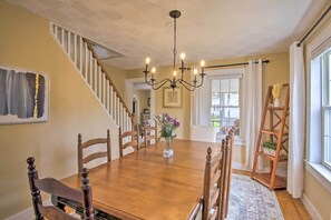 A dining room with a wooden table, chairs, a chandelier, and a staircase. - Modern Home ~ 2 Mi to Cranmore Mountain Resort! (Conway)