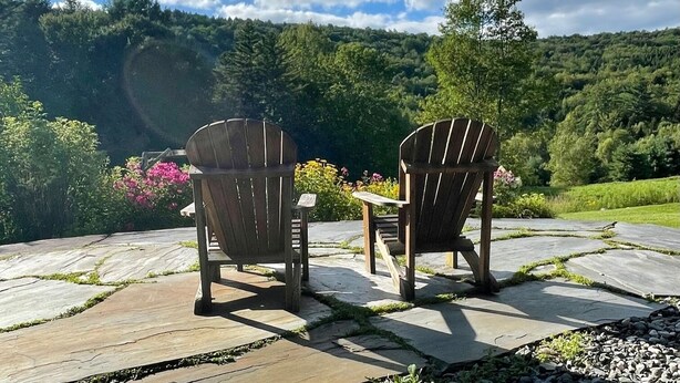 Two Adirondack chairs facing a scenic view of a lush green landscape and a clear blue sky. - Spacious Villa with Beautiful Views and Great Energy!!! (Stowe)