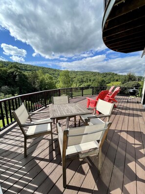 A wooden deck with a table and chairs, overlooking a forested hillside. - Spacious Villa with Beautiful Views and Great Energy!!! (Stowe)