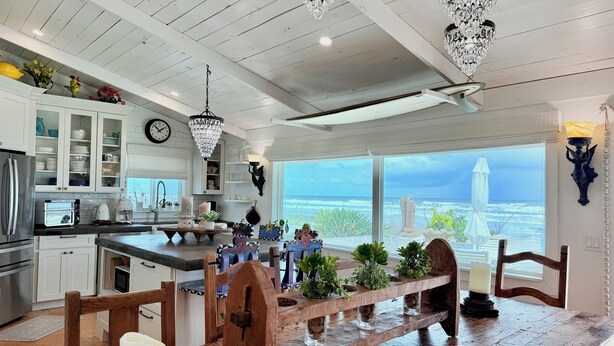 A modern kitchen with white cabinetry, a wooden island, and a view of the ocean.