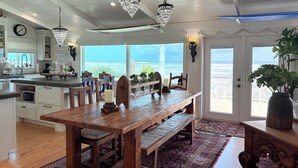 A spacious kitchen with a wooden table and bench, a view of the ocean, and a large window.