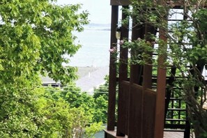 Une pergola en bois offrant une vue sur une étendue d’eau et une côte lointaine.