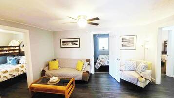 Une pièce comprenant un lit superposé, un canapé, une table basse et un ventilateur de plafond.